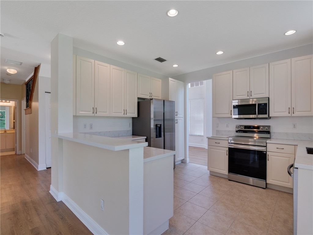 1923 Grey Falcon Circle Southwest Vero Beach, FL 32962 - Photo 12 of 36 a kitchen with stainless steel appliances granite countertop a refrigerator oven a sink a stove and white cabinets with wooden floor