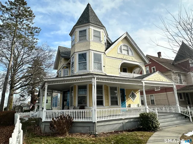 a view of a white house with a small yard and plants