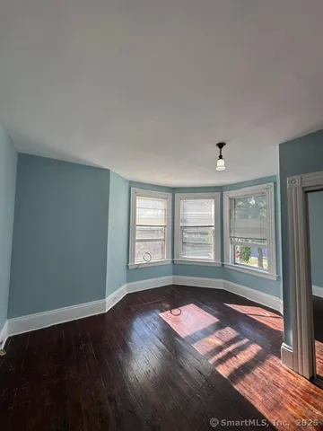 a view of empty room with wooden floor and floor to ceiling window