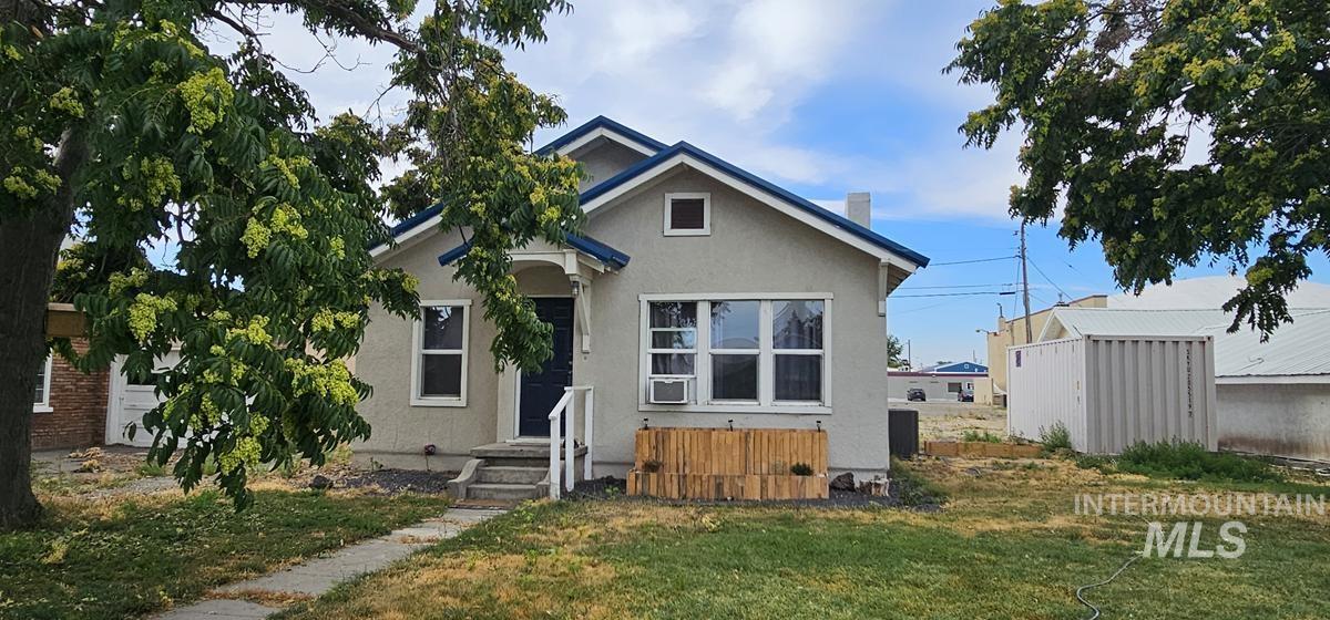 View of front of property featuring stucco siding, a front lawn, and a chimney