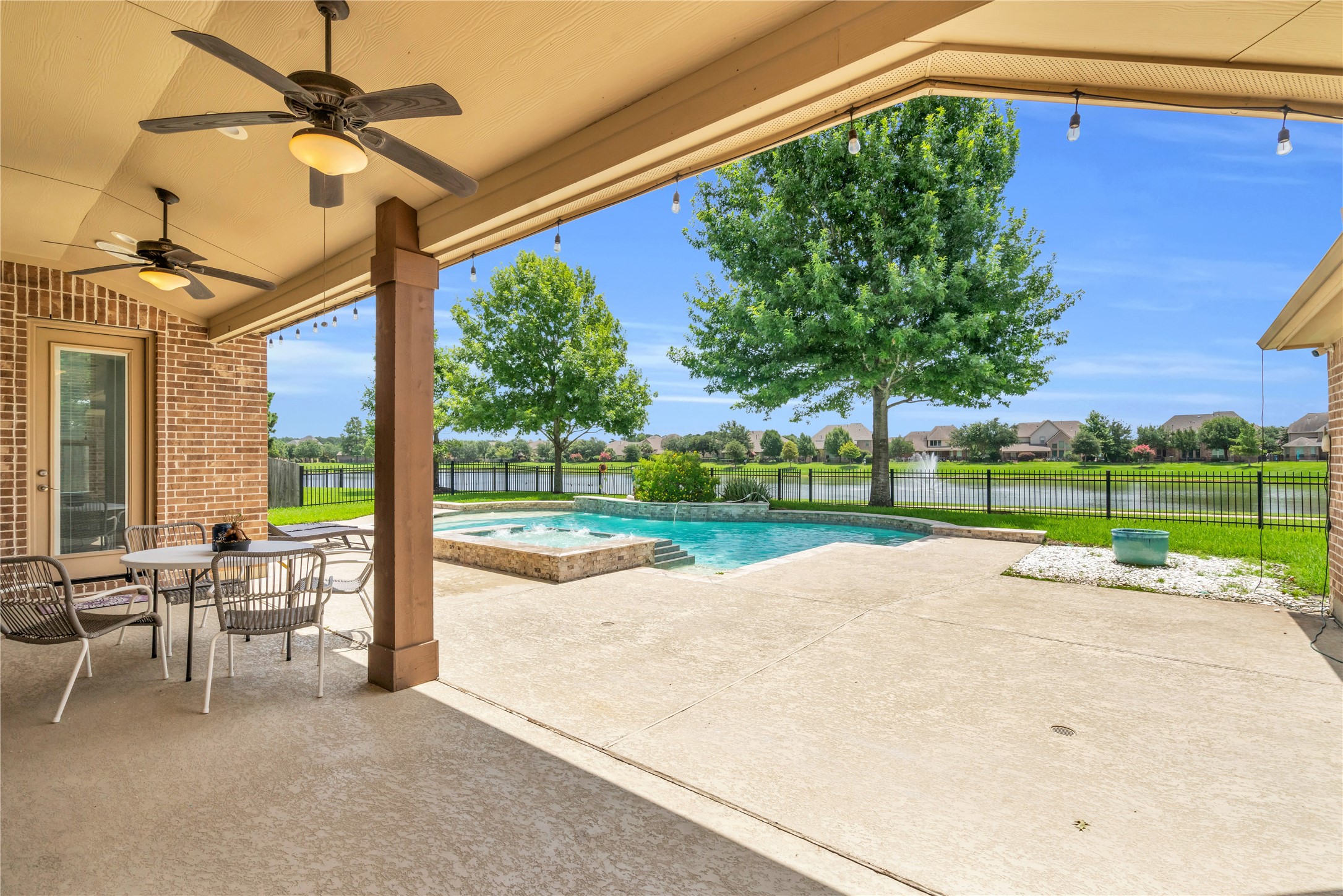 9842 Kirkstone Terrace Drive Spring, TX 77379 - Photo 23 of 34 a covered patio with ceiling fans, a dining area, and a view of the pool/hot tub. Beyond the pool, your fenced yard with a view of a serene lake providing a peaceful and scenic backdrop.