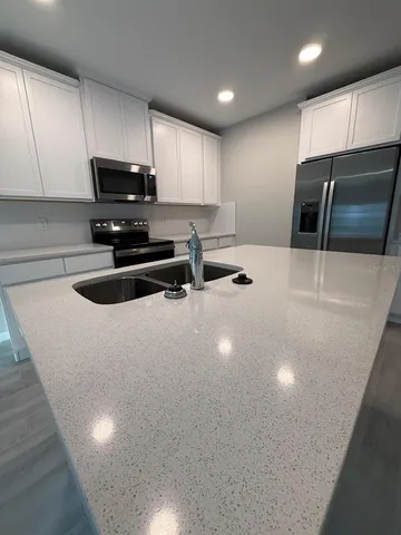 a kitchen with stainless steel appliances a sink a stove a microwave a refrigerator a counter top space and cabinets