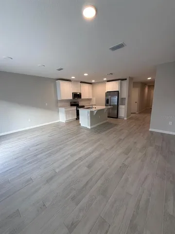 an empty room with wooden floor and stainless steel appliances