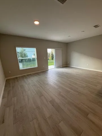 an empty room with wooden floor and windows
