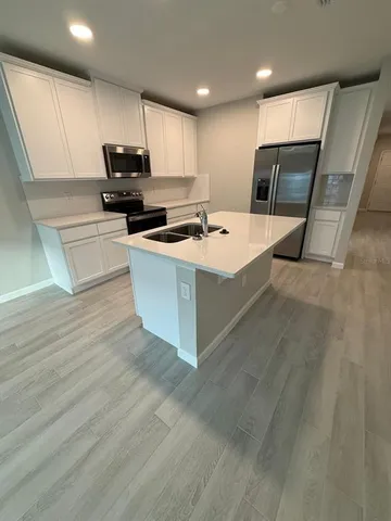 a large kitchen with stainless steel appliances granite countertop a stove a sink and a refrigerator