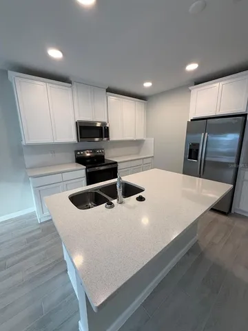 a kitchen with stainless steel appliances a white stove top oven a sink dishwasher and a refrigerator with wooden floor