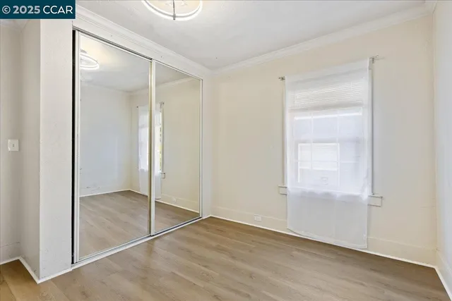 a view of an empty room with wooden floor and closet