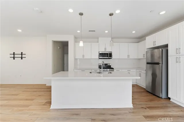 a large kitchen with stainless steel appliances kitchen island a large counter top and a refrigerator
