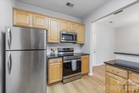 a view of an empty room with wooden floor fireplace and a window
