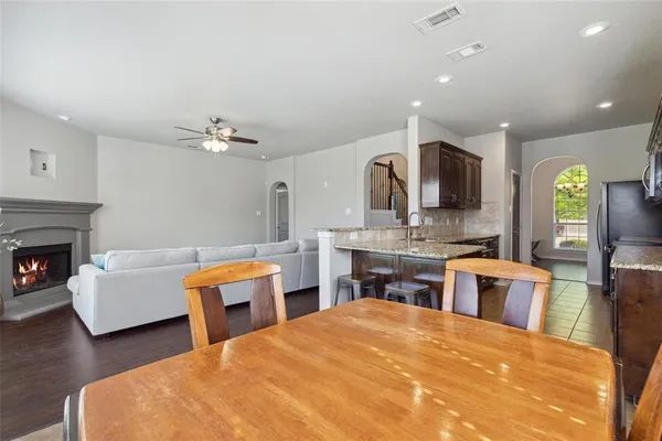 a large white kitchen with a stove a sink dishwasher and a fireplace with wooden floor