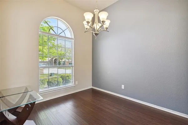 a view of empty room with wooden floor and chandelier
