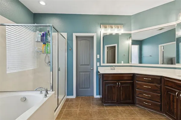 a spacious bathroom with a tub sink and mirror