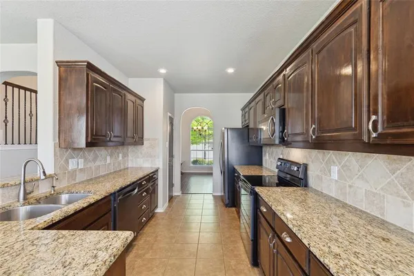 a kitchen with stainless steel appliances granite countertop a sink stove and refrigerator