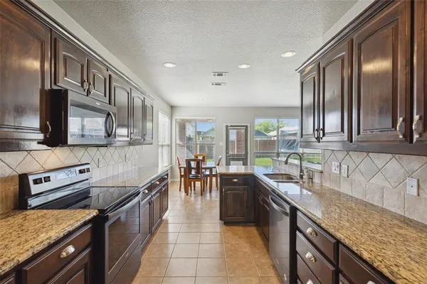 a kitchen with stainless steel appliances granite countertop a sink a stove and a wooden cabinets