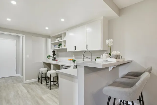 a kitchen with a sink chairs and white cabinets