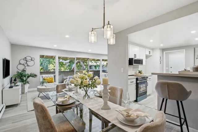 a kitchen with stainless steel appliances granite countertop a stove a refrigerator a kitchen island a table and chairs in it