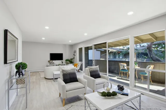 a living room with furniture a flat screen tv and a large window