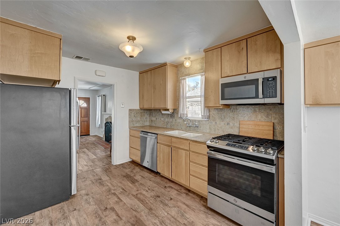 629 L Avenue Boulder City, NV 89005 - Photo 18 of 46 Kitchen featuring light wood finish cabinets, stainless steel appliances, tasteful backsplash, and light wood-type flooring