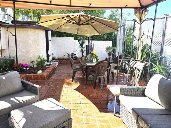 a view of a patio with couches table and chairs under an umbrella