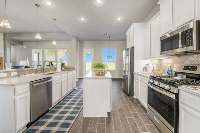 a white kitchen with stainless steel appliances granite countertop a stove and a sink