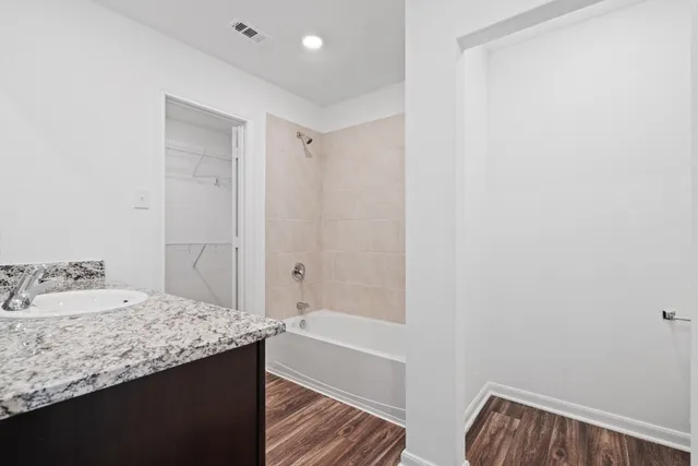 a bathroom with a granite countertop sink and a bathtub