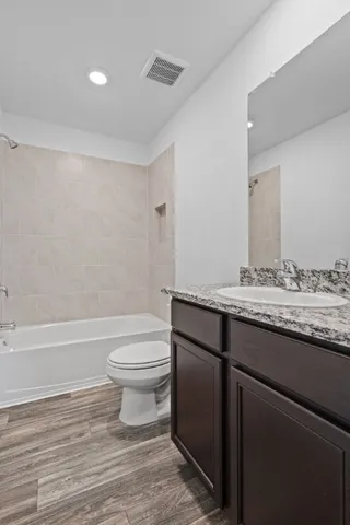 a bathroom with a granite countertop sink a toilet and bathtub