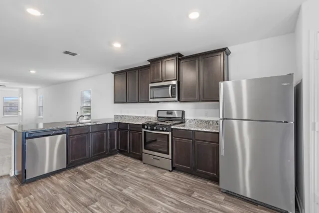 a kitchen with stainless steel appliances granite countertop a refrigerator and a stove top oven