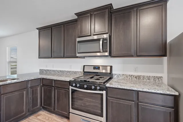 a kitchen with granite countertop cabinets stainless steel appliances and a counter space