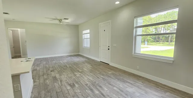 a view of an empty room with wooden floor and a window