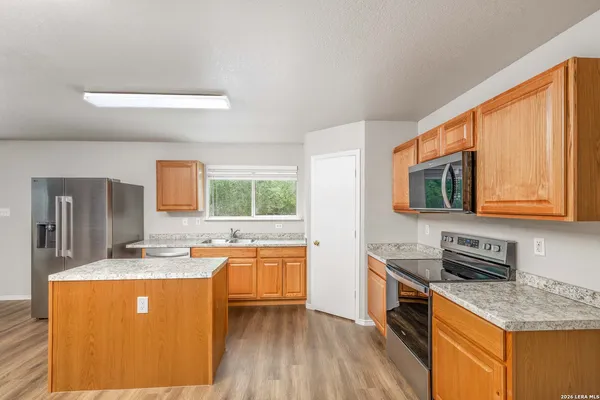 a kitchen with stainless steel appliances granite countertop wooden cabinets a stove a sink and a microwave