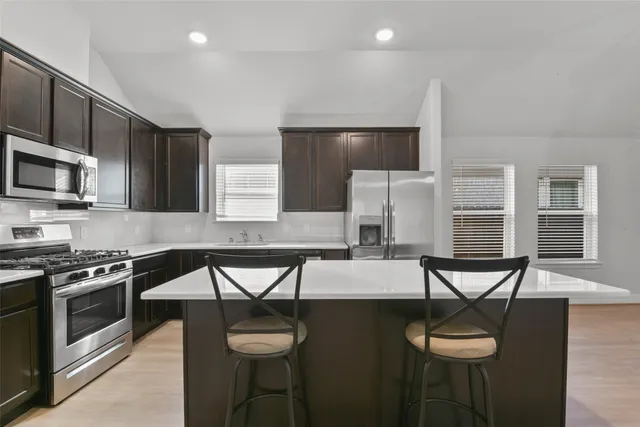 a kitchen with a table chairs microwave and cabinets