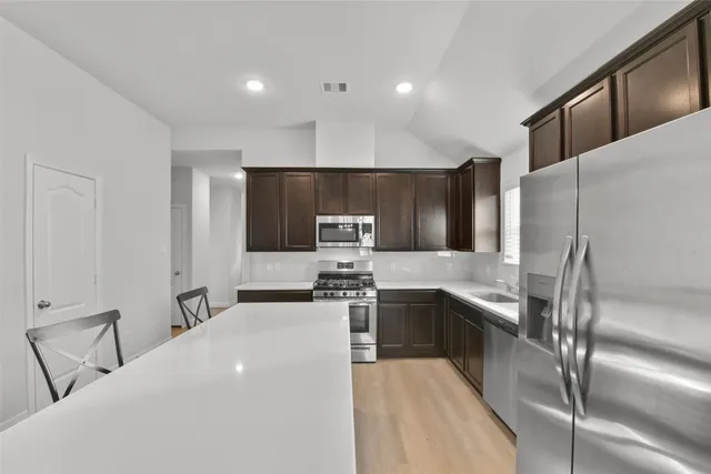 a kitchen with stainless steel appliances granite countertop a refrigerator and a stove top oven