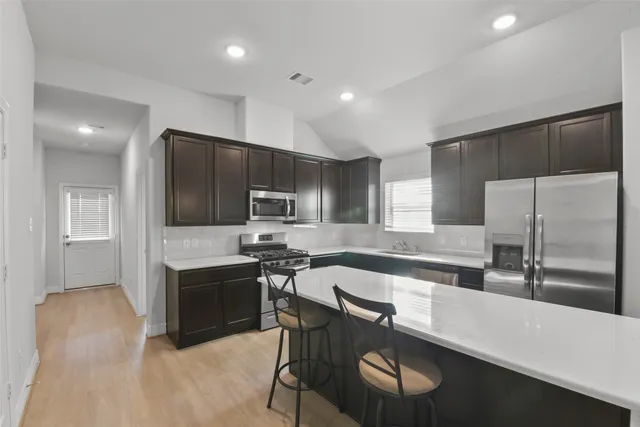 a kitchen with stainless steel appliances a stove a sink a microwave a refrigerator and cabinets