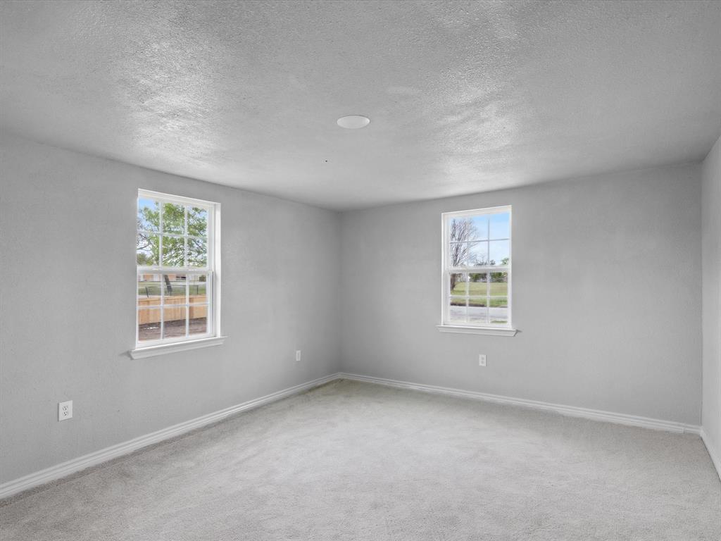 107 East Riley Street Bowie, TX 76230 - Photo 22 of 32 Spare room featuring a wealth of natural light, baseboards, carpet, and a textured ceiling