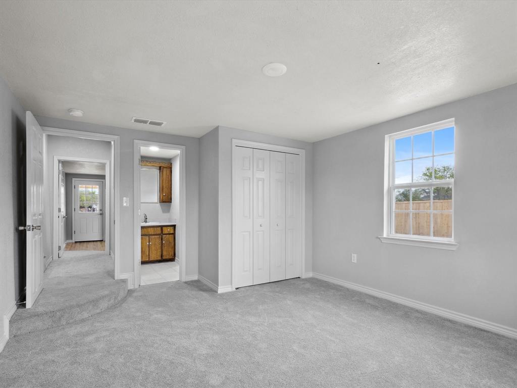 107 East Riley Street Bowie, TX 76230 - Photo 25 of 32 Unfurnished bedroom featuring light colored carpet, visible vents, multiple windows, and baseboards