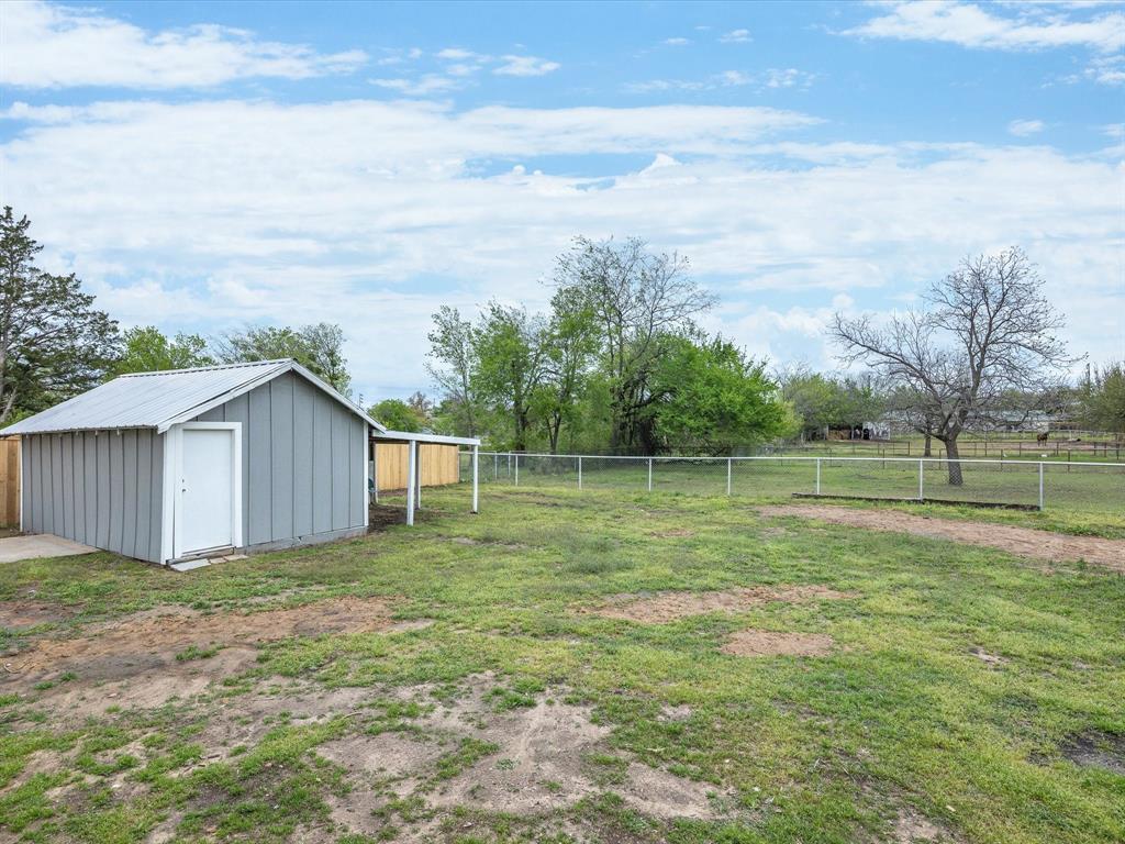 107 East Riley Street Bowie, TX 76230 - Photo 28 of 32 View of yard with an outbuilding, fence, and a storage unit