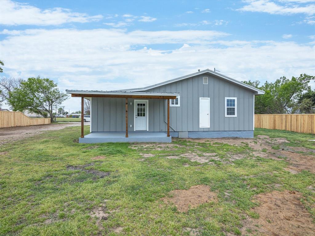 107 East Riley Street Bowie, TX 76230 - Photo 30 of 32 Back of property with metal roof, fence, board and batten siding, and a yard