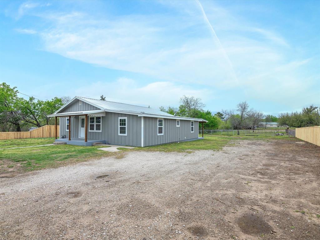 107 East Riley Street Bowie, TX 76230 - Photo 6 of 32 Rear view of house featuring fence and metal roof