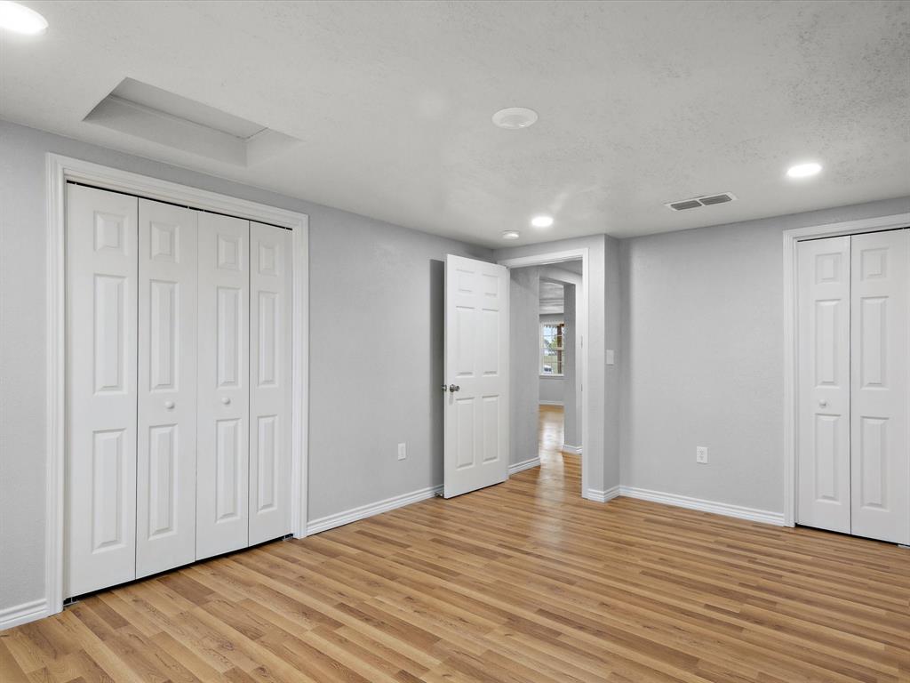 107 East Riley Street Bowie, TX 76230 - Photo 9 of 32 Unfurnished bedroom with baseboards, multiple closets, visible vents, and light wood-style floors