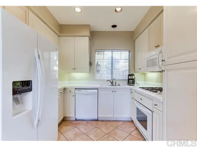 a kitchen with white cabinets and appliances