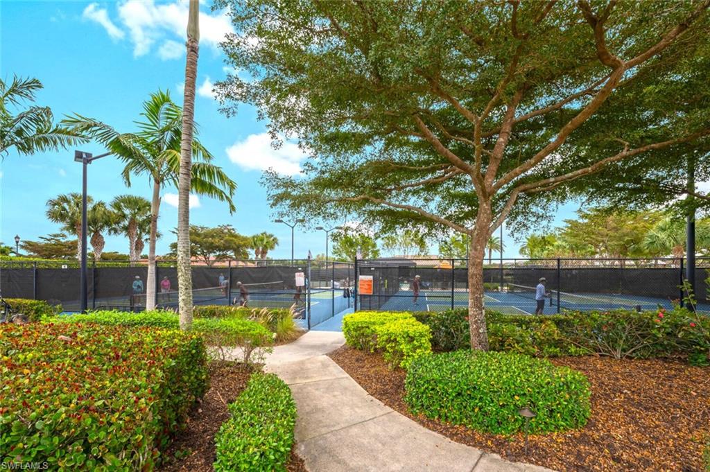 8416 Rosa Court Naples, FL 34114 - Photo 29 of 34 Concrete pathway leading to multiple enclosed tennis courts with black fencing and surrounding landscape lighting