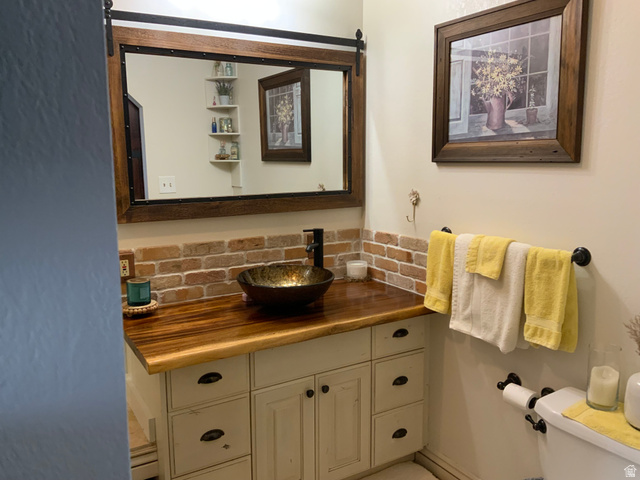 1061 Copper Street Stockton, UT 84071 - Photo 27 of 43 Vanity with a wood-finish countertop, vessel sink, and brick-style backsplash