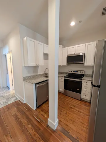 a view of a hallway with wooden floor and a bathroom