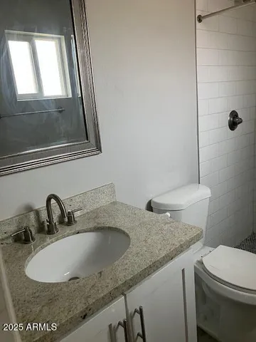 a bathroom with a granite countertop sink a mirror and a toilet