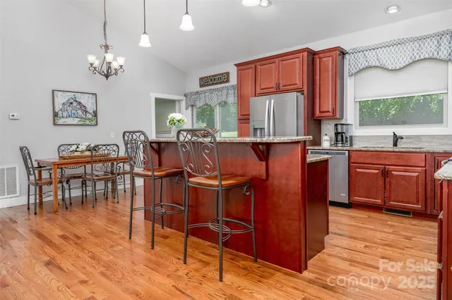 a kitchen with stainless steel appliances granite countertop a stove a sink dishwasher and cabinets with wooden floor