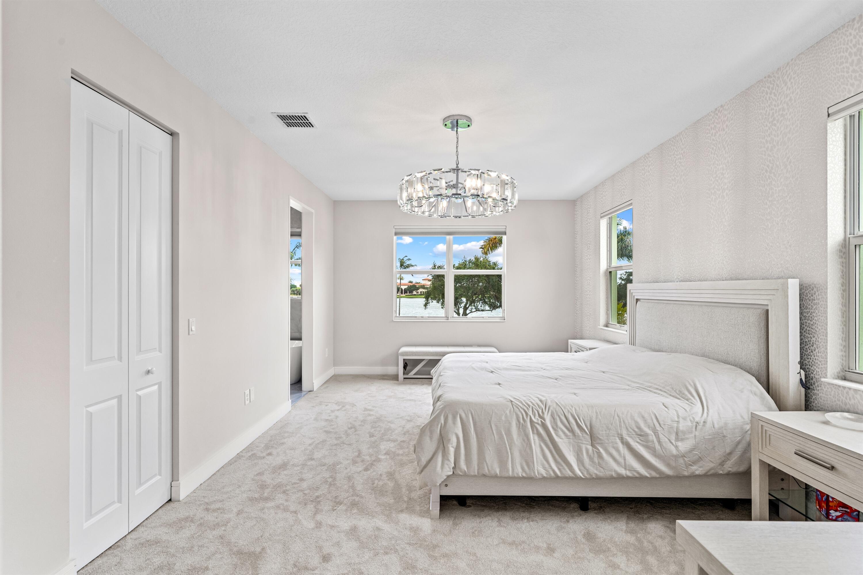 1570 Northwest 48th Place Boca Raton, FL 33431 - Photo 17 of 30 a bedroom with a bed and a chandelier
