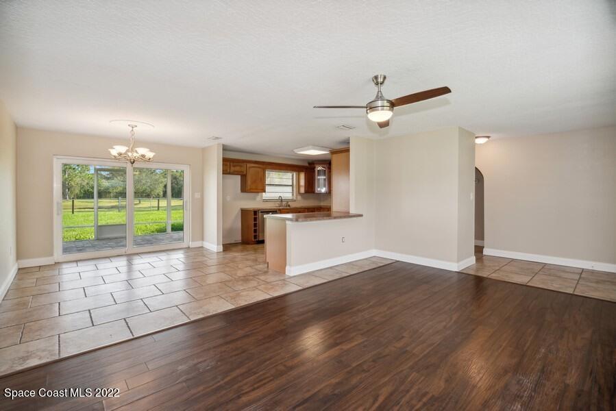 1840 Britt Road Cocoa, FL 32926 - Photo 4 of 17 an empty room with wooden floor a ceiling fan and a kitchen view