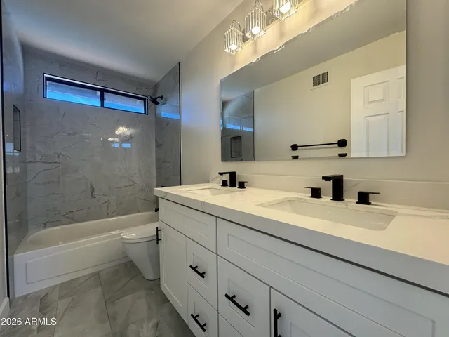 a spacious bathroom with a granite countertop sink a mirror and a shower