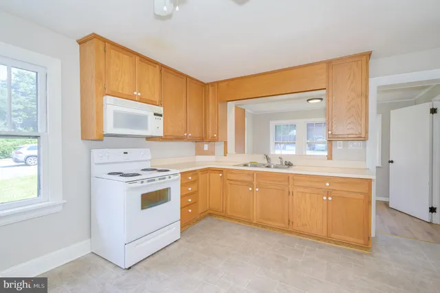 a large white kitchen with a stove a sink dishwasher and a refrigerator
