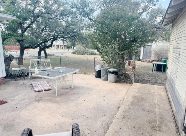 a view of a backyard with table and chairs potted plants and large tree